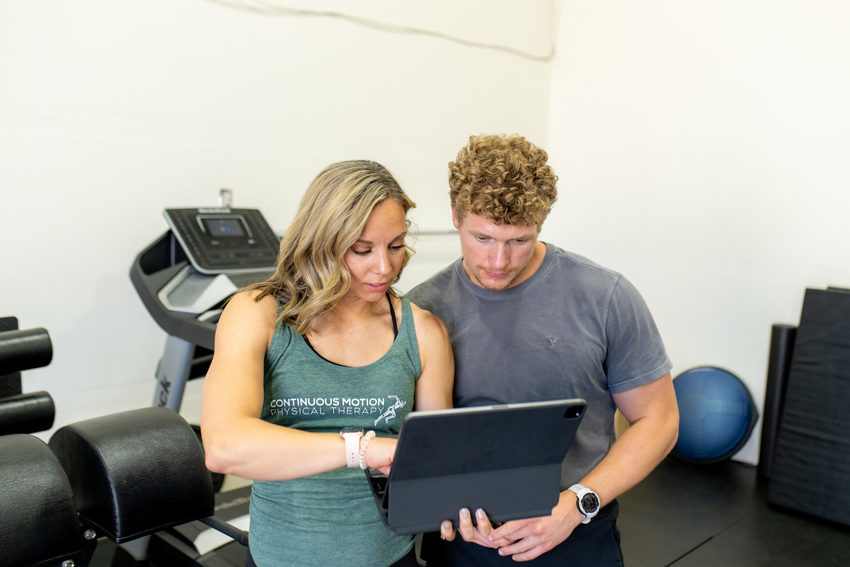 A man and woman looking at an ipad in a gym.